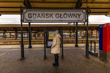 Gdansk ana tren istasyonu, bir kadın Gdansk Polonya tabelasının yanında duruyor.