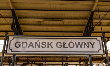 Gdansk ana tren istasyonu, bir kadın Gdansk Polonya tabelasının yanında duruyor.