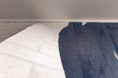 Yatak odasındaki duvardan eski duvar kağıtlarını sökmek, apartman tadilatı, evdeki duvar kağıtlarını yenilemek, duvara plastik duvar kağıdı yapıştırmak.