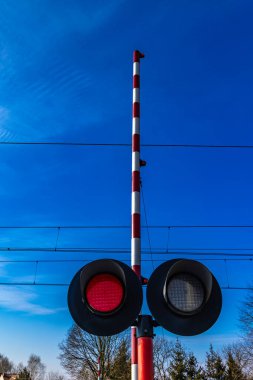 Demiryolu kavşağındaki trafik ışıkları, rayların önündeki kırmızı ışık, raylara giriş yok, tren güneşli.