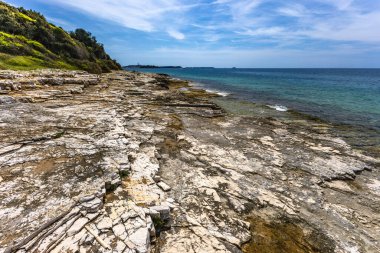 Adriyatik Denizi kıyısındaki boş kumsal, kristal su, mavi gökyüzü, kayalık sahil, Aşıklar Şehri yakınlarındaki İstrian Yarımadası 'nda dinlenme Rovinj
