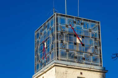 Mavi gökyüzüne karşı yüksek bir kulede eski bir saat, belediye kulesindeki saat.