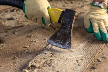 Eldivenli kadın beton zemini baltayla parçalıyor, fayansları temizliyor, döşemeleri söküyor, fayansları terrac 'a seriyor.