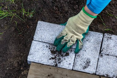 Koruyucu eldivenler, bahçeye granit kaldırım taşları döşemek, yazlık teras inşa etmek.