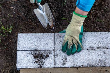 Koruyucu eldivenler, bahçeye granit kaldırım taşları döşemek, yazlık teras inşa etmek.
