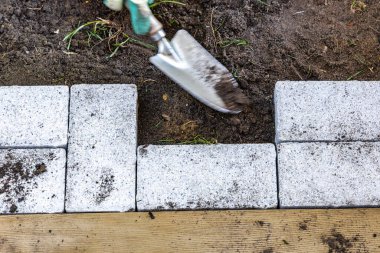Bahçeye kaldırım taşı döşeme, kaldırım taşlarının altına kum dökme, homurdanmayı ve dengelemeyi bitiren çalışmalar