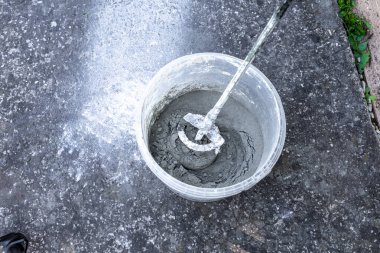 Balkona fayansları, konteynırları ve karıştırıcıyı yapıştırmak için harç ve zamk harcı harmanlıyorum.