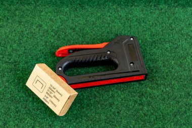 Bahçedeki evin ön cephesine yapay sarmaşık takmak bahçeye süsleme olarak yapay yapraklı bir ağ takmak, zımba takmak için bir raptiye.