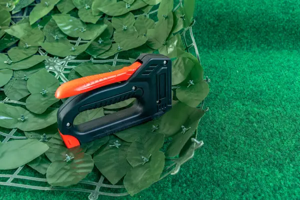 Bahçedeki evin ön cephesine yapay sarmaşık takmak bahçeye süsleme olarak yapay yapraklı bir ağ takmak, zımba takmak için bir raptiye.