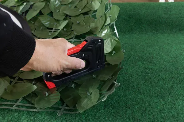 Bahçedeki evin ön cephesine yapay sarmaşık takmak bahçeye süsleme olarak yapay yapraklı bir ağ takmak, zımba takmak için bir raptiye.