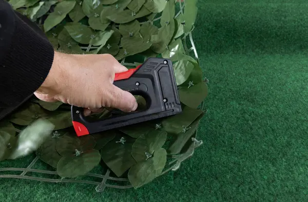 Bahçedeki evin ön cephesine yapay sarmaşık takmak bahçeye süsleme olarak yapay yapraklı bir ağ takmak, zımba takmak için bir raptiye.