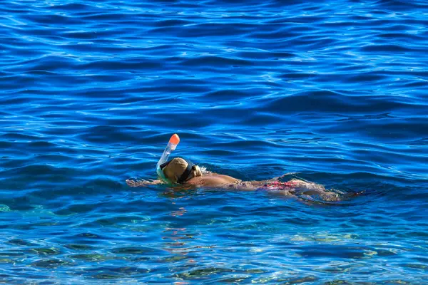 Bir kadın, Akdeniz 'in mavi ve berrak sularına yüzme maskesiyle dalmayı öğreniyor Hırvatistan
