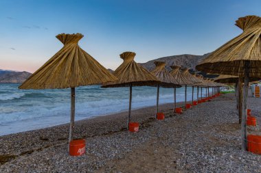 KRK adasındaki Baska plajında güneş gözlüğü, Hırvatistan 'da turizm sezonuna hazırlık, beac' ta şemsiye kurma