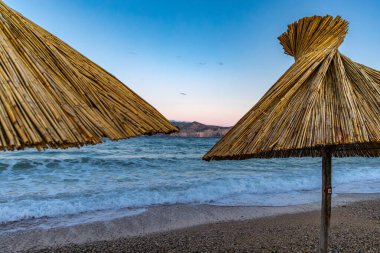 KRK adasındaki Baska plajında güneş gözlüğü, Hırvatistan 'da turizm sezonuna hazırlık, beac' ta şemsiye kurma