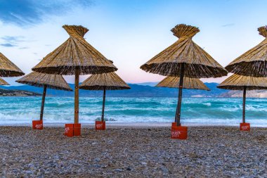 KRK adasındaki Baska plajında güneş gözlüğü, Hırvatistan 'da turizm sezonuna hazırlık, beac' ta şemsiye kurma