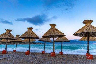 KRK adasındaki Baska plajında güneş gözlüğü, Hırvatistan 'da turizm sezonuna hazırlık, beac' ta şemsiye kurma