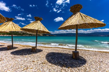 KRK adasındaki Baska plajında güneş gözlüğü, Hırvatistan 'da turizm sezonuna hazırlık, beac' ta şemsiye kurma