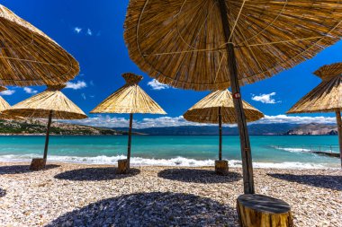 KRK adasındaki Baska plajında güneş gözlüğü, Hırvatistan 'da turizm sezonuna hazırlık, beac' ta şemsiye kurma