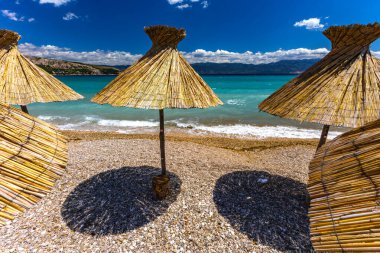 KRK adasındaki Baska plajında güneş gözlüğü, Hırvatistan 'da turizm sezonuna hazırlık, beac' ta şemsiye kurma