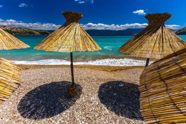 KRK adasındaki Baska plajında güneş gözlüğü, Hırvatistan 'da turizm sezonuna hazırlık, beac' ta şemsiye kurma