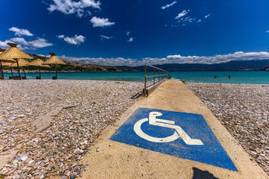 KRK adasındaki Baska plajında güneş gözlüğü, Hırvatistan 'da turizm sezonuna hazırlık, beac' ta şemsiye kurma