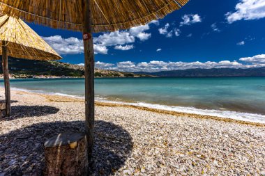 KRK adasındaki Baska plajında güneş gözlüğü, Hırvatistan 'da turizm sezonuna hazırlık, beac' ta şemsiye kurma