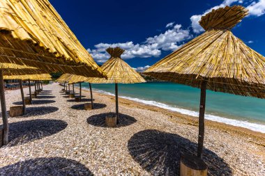 KRK adasındaki Baska plajında güneş gözlüğü, Hırvatistan 'da turizm sezonuna hazırlık, beac' ta şemsiye kurma