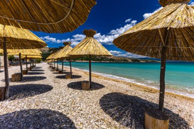 KRK adasındaki Baska plajında güneş gözlüğü, Hırvatistan 'da turizm sezonuna hazırlık, beac' ta şemsiye kurma