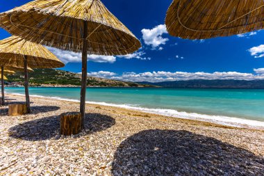 KRK adasındaki Baska plajında güneş gözlüğü, Hırvatistan 'da turizm sezonuna hazırlık, beac' ta şemsiye kurma