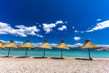 KRK adasındaki Baska plajında güneş gözlüğü, Hırvatistan 'da turizm sezonuna hazırlık, beac' ta şemsiye kurma