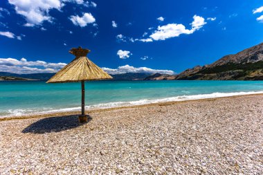 KRK adasındaki Baska plajında güneş gözlüğü, Hırvatistan 'da turizm sezonuna hazırlık, beac' ta şemsiye kurma