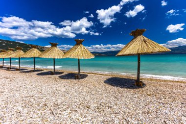 KRK adasındaki Baska plajında güneş gözlüğü, Hırvatistan 'da turizm sezonuna hazırlık, beac' ta şemsiye kurma