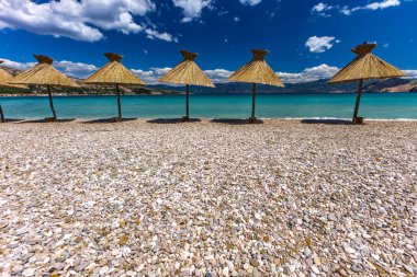 KRK adasındaki Baska plajında güneş gözlüğü, Hırvatistan 'da turizm sezonuna hazırlık, beac' ta şemsiye kurma