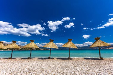 KRK adasındaki Baska plajında güneş gözlüğü, Hırvatistan 'da turizm sezonuna hazırlık, beac' ta şemsiye kurma