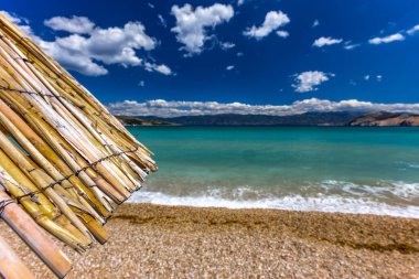 KRK adasındaki Baska plajında güneş gözlüğü, Hırvatistan 'da turizm sezonuna hazırlık, beac' ta şemsiye kurma