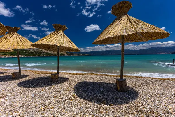 KRK adasındaki Baska plajında güneş gözlüğü, Hırvatistan 'da turizm sezonuna hazırlık, beac' ta şemsiye kurma