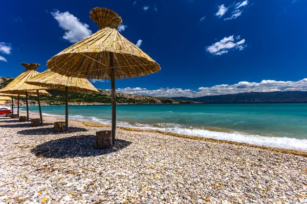 KRK adasındaki Baska plajında güneş gözlüğü, Hırvatistan 'da turizm sezonuna hazırlık, beac' ta şemsiye kurma