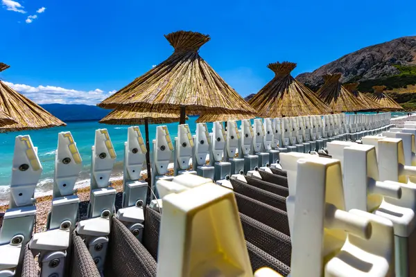 KRK adasındaki Baska plajında güneş gözlüğü, Hırvatistan 'da turizm sezonuna hazırlık, beac' ta şemsiye kurma