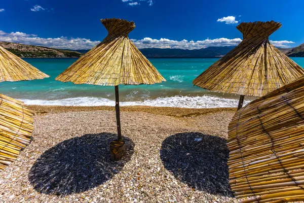 KRK adasındaki Baska plajında güneş gözlüğü, Hırvatistan 'da turizm sezonuna hazırlık, beac' ta şemsiye kurma