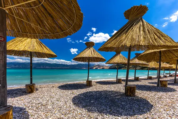 KRK adasındaki Baska plajında güneş gözlüğü, Hırvatistan 'da turizm sezonuna hazırlık, beac' ta şemsiye kurma