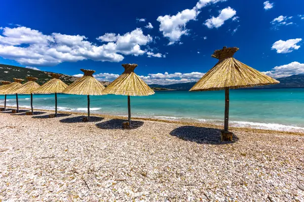 KRK adasındaki Baska plajında güneş gözlüğü, Hırvatistan 'da turizm sezonuna hazırlık, beac' ta şemsiye kurma