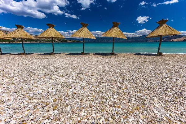 KRK adasındaki Baska plajında güneş gözlüğü, Hırvatistan 'da turizm sezonuna hazırlık, beac' ta şemsiye kurma