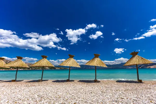 KRK adasındaki Baska plajında güneş gözlüğü, Hırvatistan 'da turizm sezonuna hazırlık, beac' ta şemsiye kurma