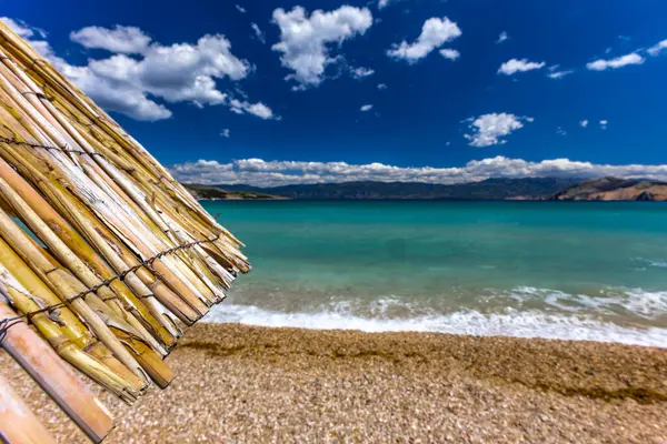 KRK adasındaki Baska plajında güneş gözlüğü, Hırvatistan 'da turizm sezonuna hazırlık, beac' ta şemsiye kurma