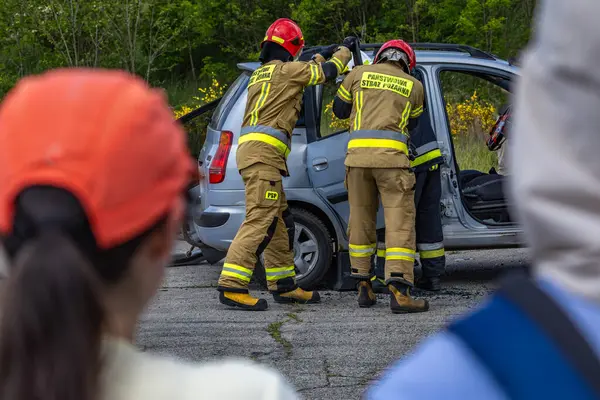 İki itfaiyeci bir arabanın kaportasını keserek bir trafik kazası sırasında arabada mahsur kalan birini çıkarmaya çalışmış.