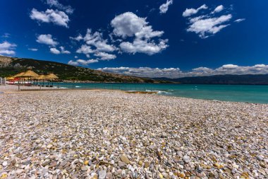 KRK adasındaki Baska 'daki boş çakıl taşı plajı, tatil sezonundan önce Hırvatistan' ın Adriyatik Denizi 'nde masmavi su