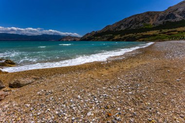 KRK adasındaki Baska 'daki boş çakıl taşı plajı, tatil sezonundan önce Hırvatistan' ın Adriyatik Denizi 'nde masmavi su