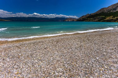 KRK adasındaki Baska 'daki boş çakıl taşı plajı, tatil sezonundan önce Hırvatistan' ın Adriyatik Denizi 'nde masmavi su