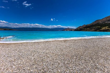 KRK adasındaki Baska 'daki boş çakıl taşı plajı, tatil sezonundan önce Hırvatistan' ın Adriyatik Denizi 'nde masmavi su