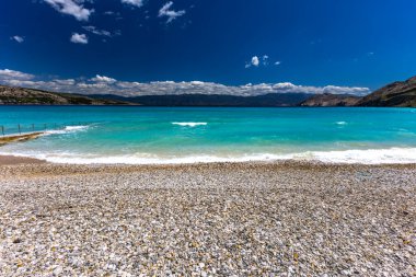 KRK adasındaki Baska 'daki boş çakıl taşı plajı, tatil sezonundan önce Hırvatistan' ın Adriyatik Denizi 'nde masmavi su